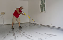 This image shows a man painting the floor with a roller.