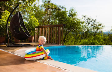 The image shows a baby with a life saver sitting on the edge of the swimming pool.