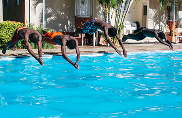 This image shows 4 men diving into a pool.